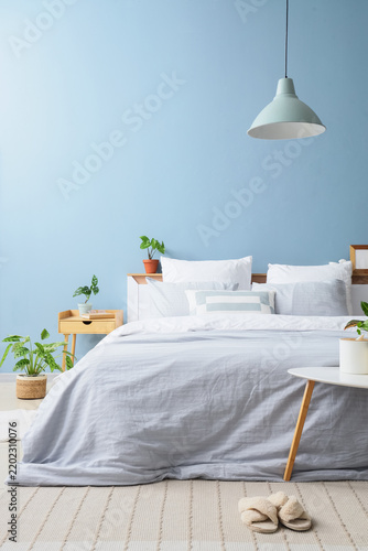 Wellness and home comfort, cozy bedroom interior with soft blue walls and ind...