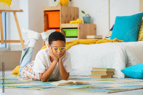 Homeschooling and childhood education, young boy reading a book on the floor ...