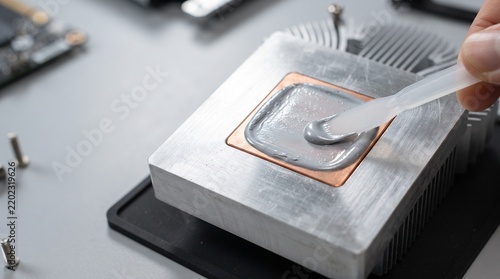 Technician applying thermal paste to a computer CPU heatsink with a spatula