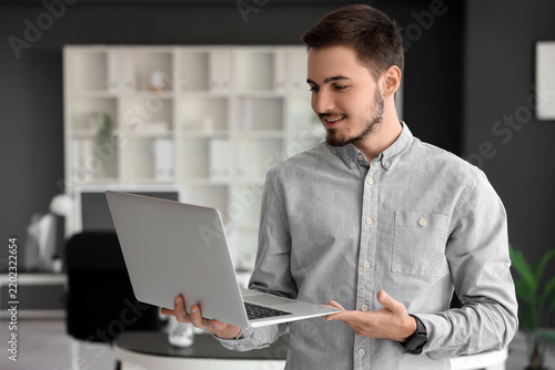 Handsome young man working with laptop in office