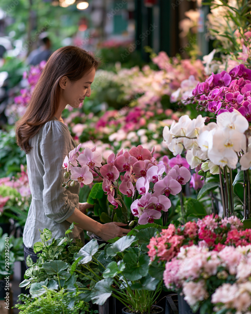 Obraz premium Woman choosing flowers at Taipei plant market