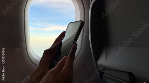 Canvas Print Close up of traveler hands holding and using a mobile smartphone inside an airpl