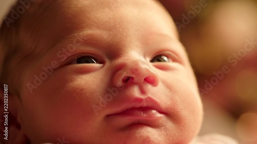 Close up portrait of a newborn infant baby face with warm lighting and gentle expression