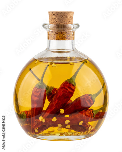 Round glass bottle of spicy chili infused oil with whole red peppers