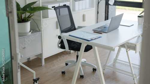 Modern minimalist home office workspace with a laptop and ergonomic chair in a bright room