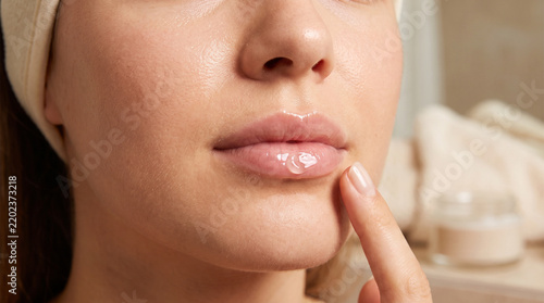 Young woman applying lip balm during winter skincare routine  