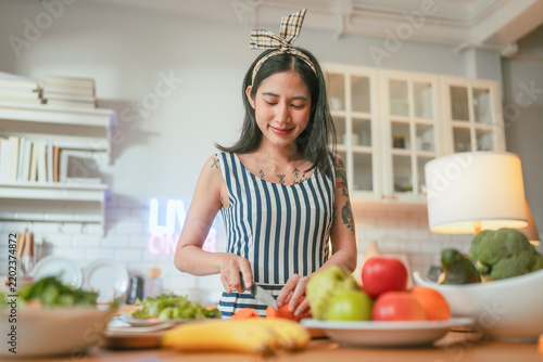 A content creator smiles while preparing colorful vegetables during a cooking livestream, capturing modern food influencer culture at home.
