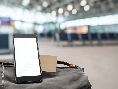 Smartphone with blank screen beside travel luggage in a modern airport terminal
