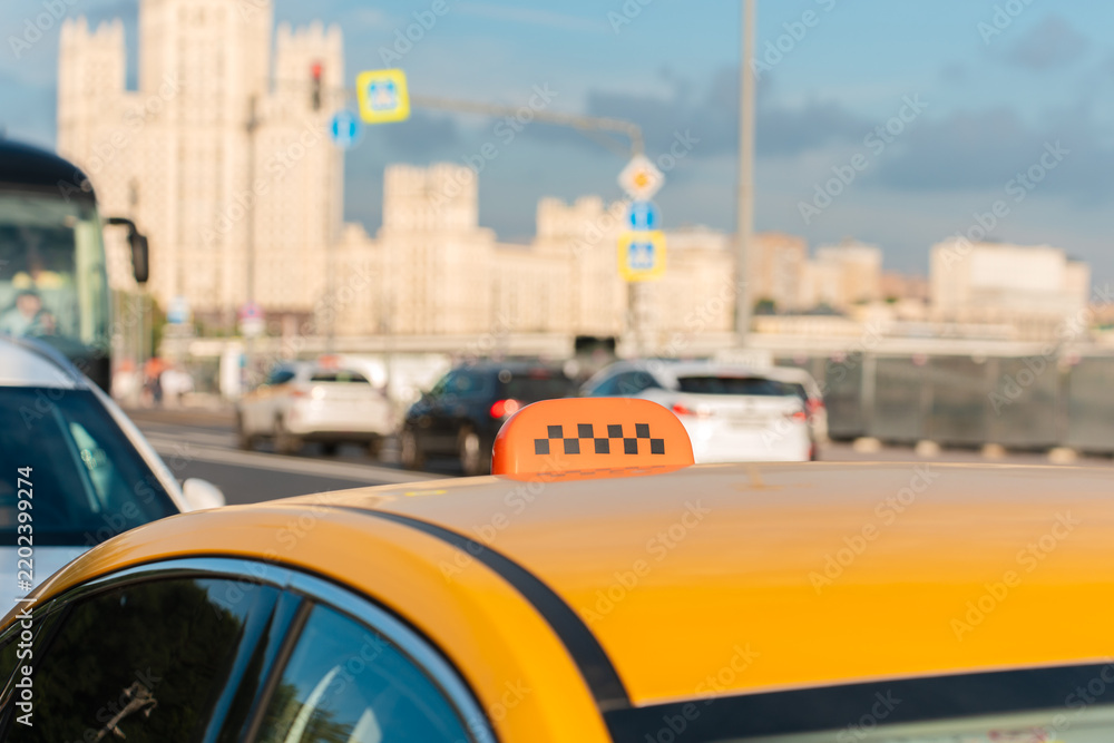 Fototapeta premium Yellow taxi with a checkered sign on a busy city street