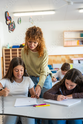 Teacher assisting students learning in a school classroom