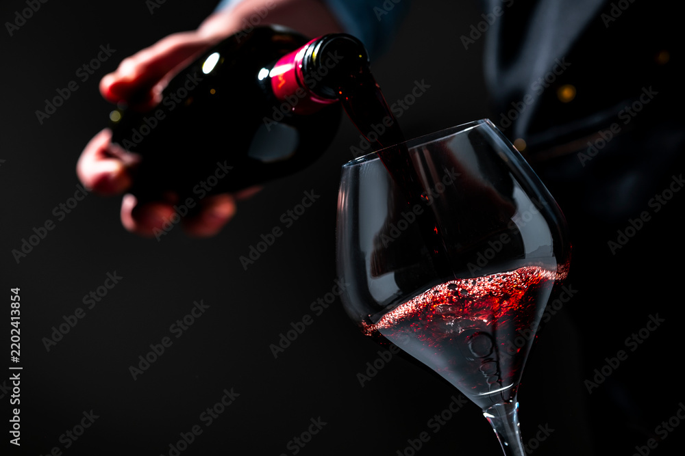 Obraz premium Premium Pinot Noir red wine in crystal glassware — professional tasting room event. Skilful sommelier with bottle serving alcohol in restaurant. Luxury lifestyle, elegant catering service.