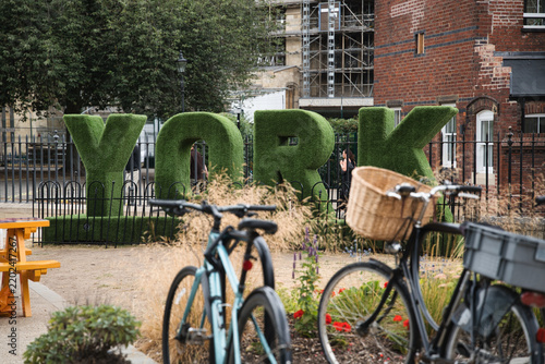 York letters crafted from lush green topiary standing prominently in a public park, with bicycles parked nearby suggesting urban exploration and sustainable travel