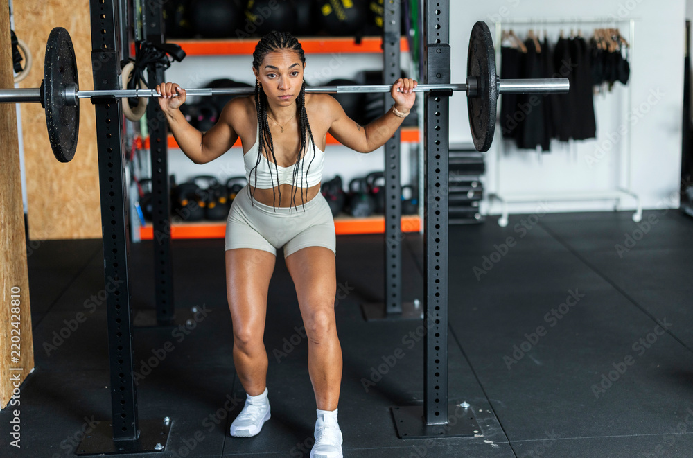 Obraz premium Determined woman squatting barbell for strength training