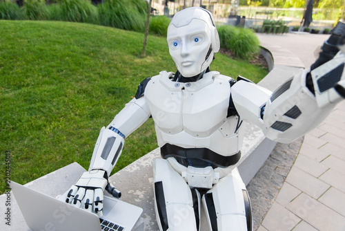 Futuristic android holding laptop and taking selfie