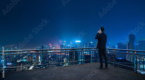Businessman talking on phone overlooking city at night