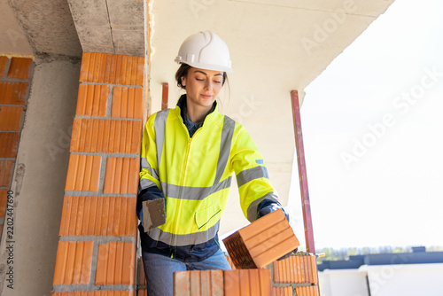 Female construction worker placing brick with trowel