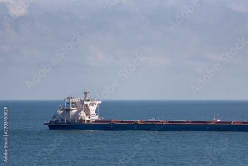 Konstfotografi Large LNG-powered bulk carrier sailing slowly across calm blue waters, with the distinctive LNG fuel tank visible near the superstructure