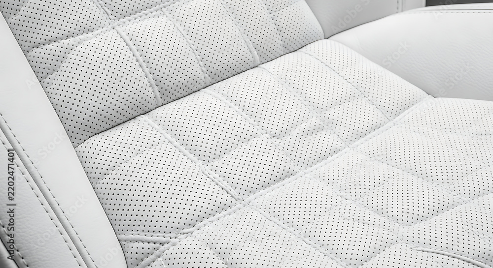 Fototapeta premium Close-up of luxury white perforated leather car seat with quilted stitching