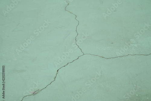 Weathered painted concrete surface of an outdoor basketball court with fine cracks and green, blue and turquoise tones, suitable for sports backgrounds, textures and abstract designs.