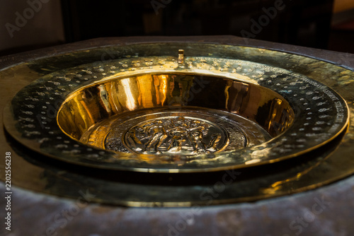Obraz na plátně Ancient ornate baptismal font with engraved brass basin inside historic church