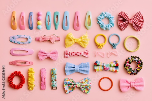 Top view flatlay of kids' hair accessories, colorful hair clips, elastic bands, and cute bows on a pastel background, children fashion concept.