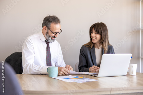 Senior businessman mentoring a young female colleague at office desk