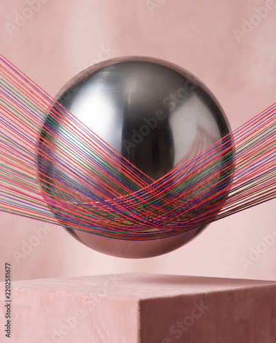 Polished metal sphere wrapped in colorful threads.