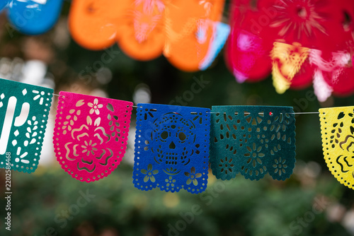 Authentic street banner ornaments with sugar skull, heart, and cactus cutouts for Latin American national holidays celebration. Traditional Mexican Heritage Papel Picado  