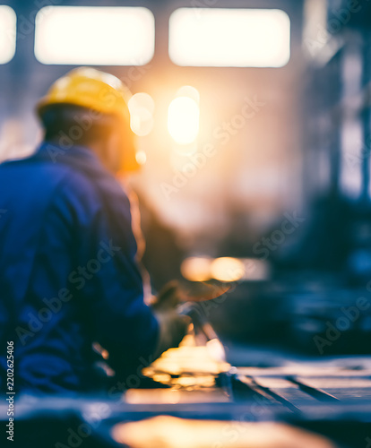 A construction worker wearing a yellow helmet operates machinery in a dimly lit industrial setting