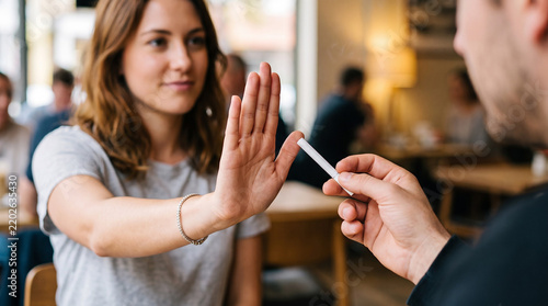 A close-up lifestyle photograph of a person holding up their hand in a stop gesture to refuse a cigarette being offered by another person. No Tobacco, No cigarette concept. No smoking concept.