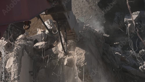 A crane demolishing a multi-story building in sunny weather.