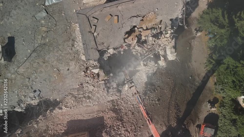 A crane demolishing a multi-story building in sunny weather.