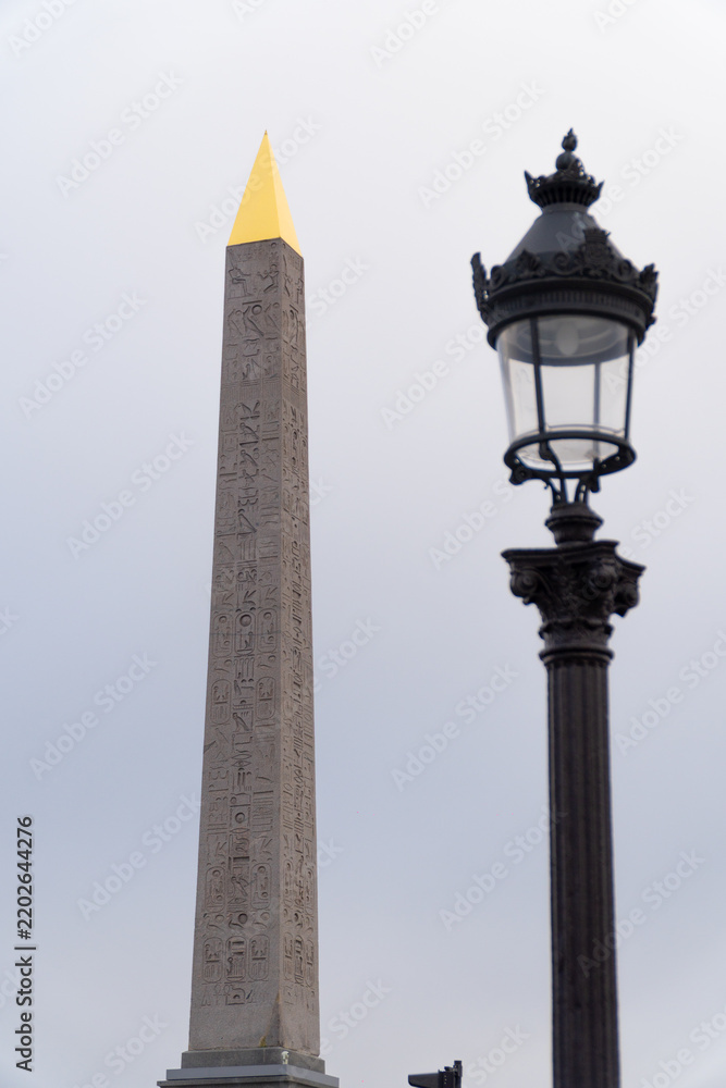 Fototapeta premium L'Obélisque de Louxor avec sa pointe dorée et un réverbère traditionnel parisien, Place de la Concorde à Paris, France.