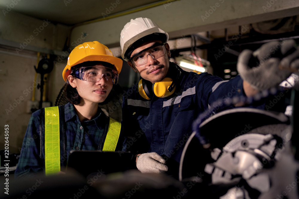 Fototapeta premium Two Industrial Technicians Collaborating to Inspect Heavy Machinery in Factory Workshop Representing Teamwork, Engineering Maintenance, Equipment Inspection and Workplace Safety