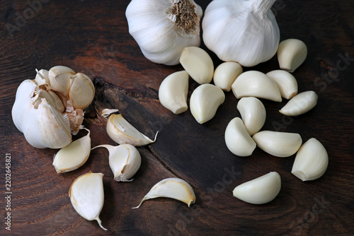Garlic cloves in a bowl with peeled garlic on wooden background