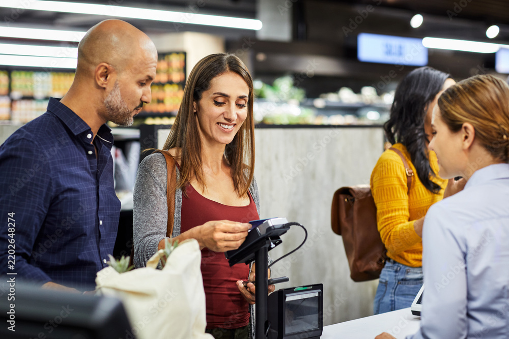 Obraz premium Credit card, grocery and payment with couple in supermarket for shopping, retail and sales. Digital transaction, discount and food coupon with happy people in store for customer and promotion code