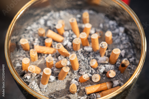 Fotografie Glass ashtray filled with used cigarette butts and tobacco ashes