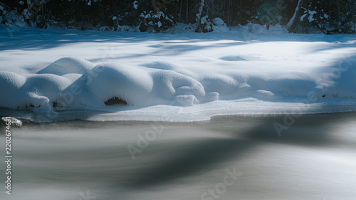 Fotografie Silky river current passing rounded snow banks in Kanas