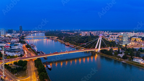 Photography Illuminated cable bridge between a city center and wooded bank
