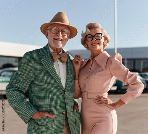 Cheesy car dealers posing on classic car lot in retro tasteless outfits.