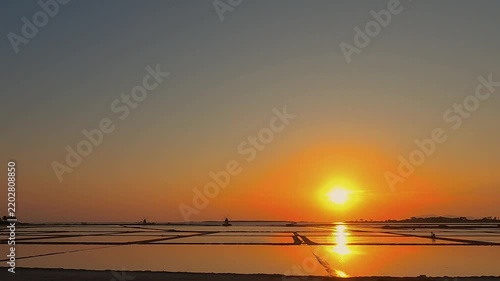 Golden sunset over tranquil salt pans near Trapani, Italy