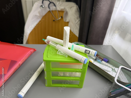 Desk supplies are arranged on a table in a room with medical equipment in the background during daytime hours
