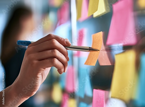 Hand with pen placing sticky notes on glass, ideas