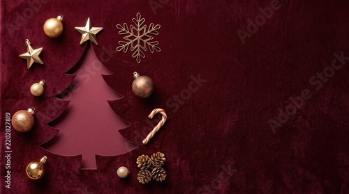 Christmas tree silhouette with golden ornaments and pine cones on a burgundy velvet background