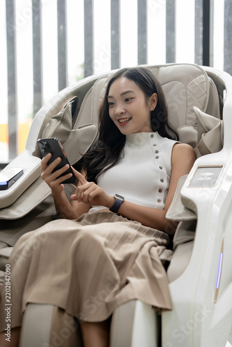 Фотография Young woman smiling, enjoying a comfortable zero gravity massage chair, browsing