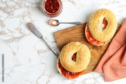 high angle view sesame seed bagel with strawberry rhubarb jam