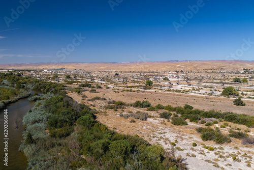 Aerial shot reveals pump jacks operating across an arid Californian oil field bordered by a river and hills, showcasing energy extraction, petroleum infrastructure, and carbon capture territory.
