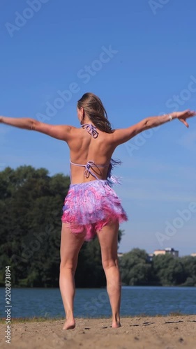 Vertical Tanned Young Woman with Perfect Model Appearance Relaxing in a Swimsuit Near the Sea
