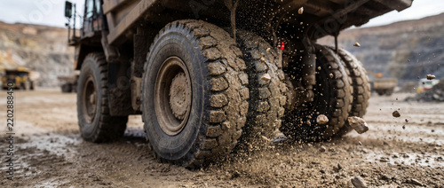 Giant dump truck tires driving through mud in an open pit mine