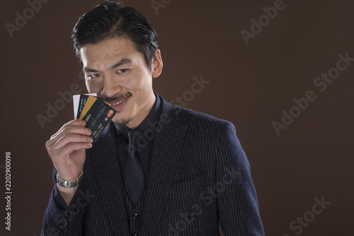 Fotografie Confident Asian businessman holding credit cards in a studio portrait